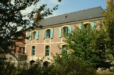 bâtiment en briques marron avec volets bleus et toiture noire